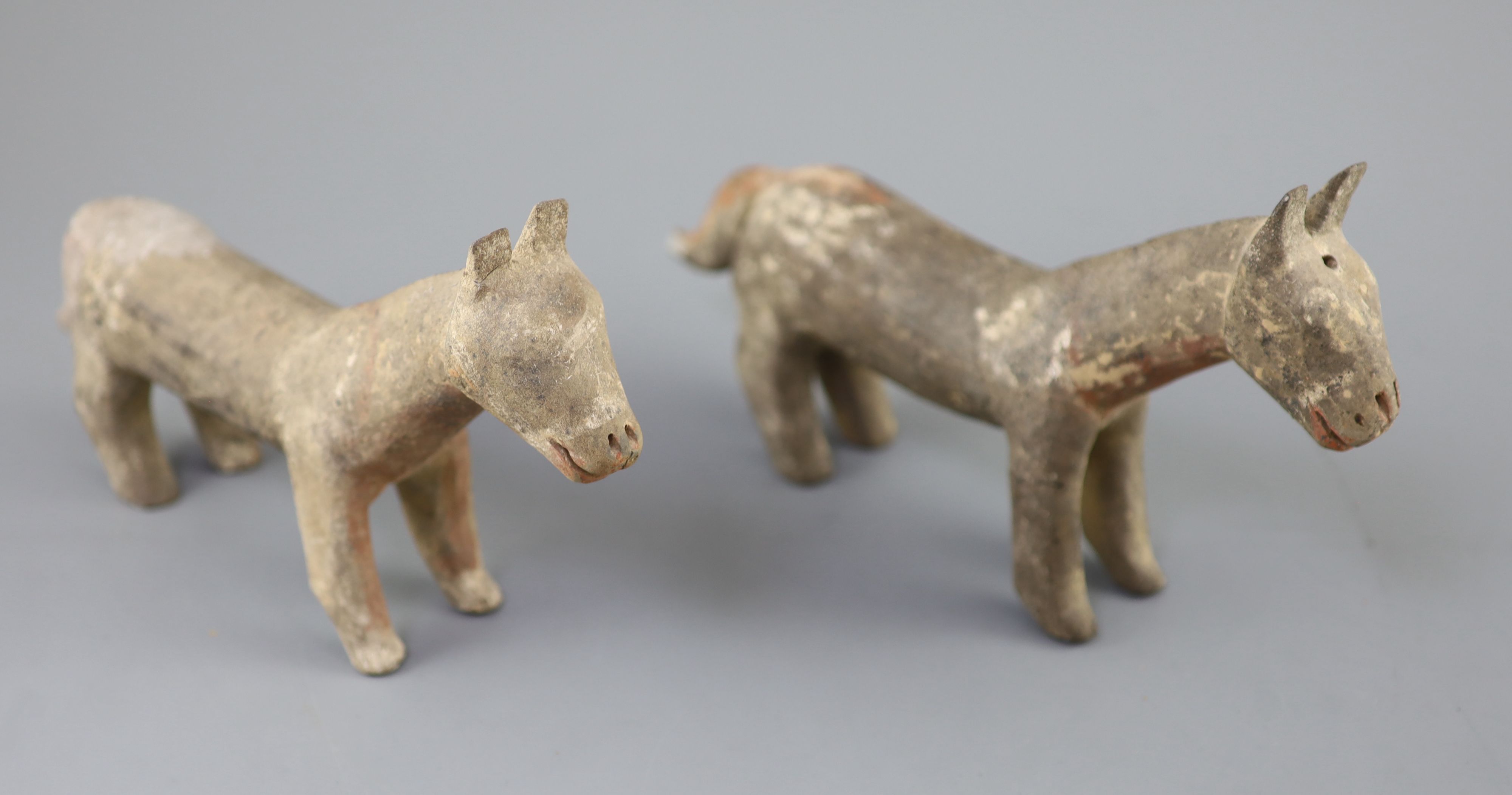 A pair of Chinese grey pottery models of dogs, Han dynasty or later, 26cm long, repairs